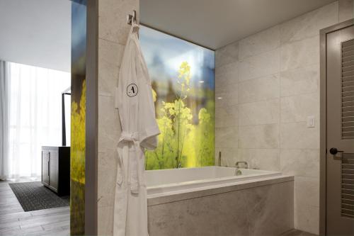 een badkamer met een bad en een groot schilderij aan de muur bij Archer Hotel Napa in Napa