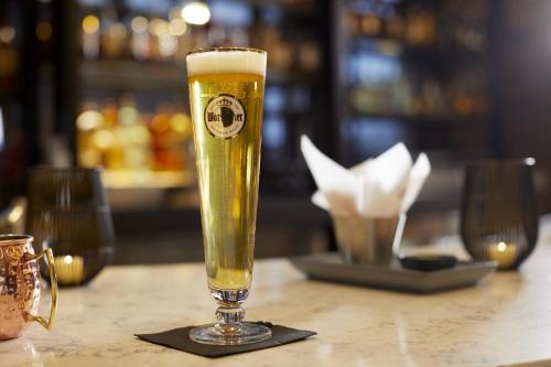 a glass of beer sitting on a table at Archer Hotel Boston/Burlington in Burlington