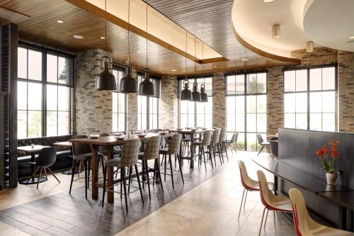 a restaurant with tables and chairs and windows at Archer Hotel Florham Park in Florham Park