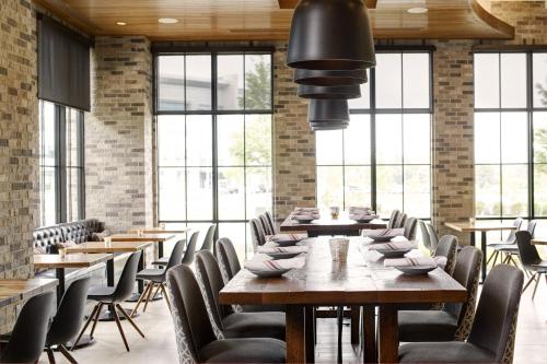 a dining room with tables and chairs and windows at Archer Hotel Florham Park in Florham Park