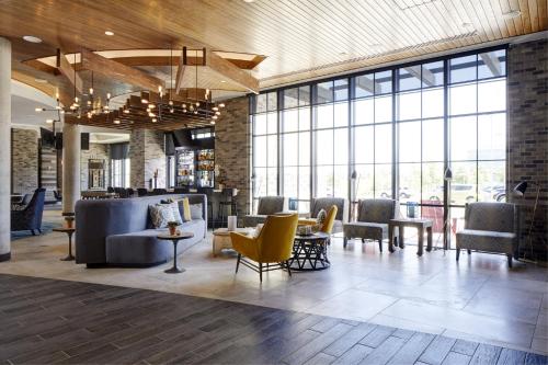 a lobby with chairs and tables and windows at Archer Hotel Florham Park in Florham Park