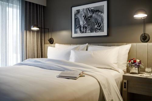 a bedroom with a bed with a book and two zebras at Archer Hotel Boston/Burlington in Burlington