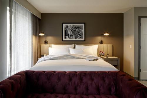 a bedroom with a large bed with a red couch at Archer Hotel Boston/Burlington in Burlington