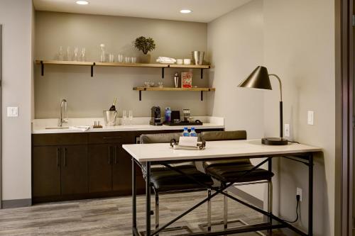 uma cozinha com uma mesa com um candeeiro e um lavatório em Archer Hotel Boston/Burlington em Burlington