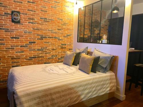 un lit dans une chambre avec un mur de briques dans l'établissement Petit cocon vue sur la Loire avec Place de Parking offerte, à Orléans