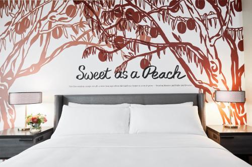 a bedroom with a bed with a tree wall decal at Archer Hotel Tysons in Tysons Corner