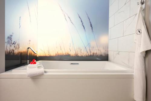 a bath tub in a bathroom with a painting on the wall at Archer Hotel Tysons in Tysons Corner