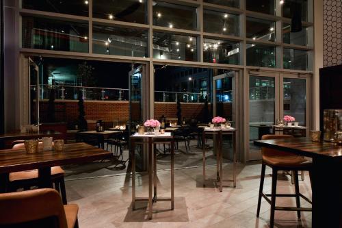 a restaurant with tables and chairs and windows at Archer Hotel Tysons in Tysons Corner