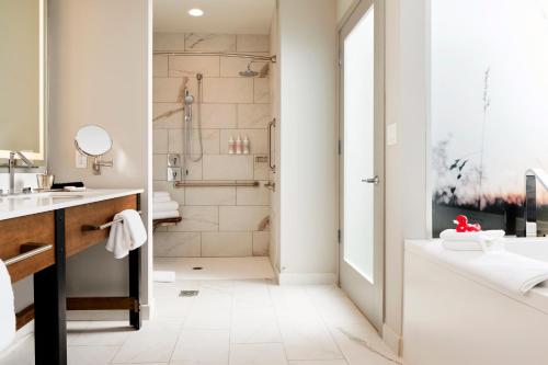 a bathroom with a shower and a sink and a tub at Archer Hotel Tysons in Tysons Corner