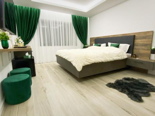 a bedroom with a large bed and a green chair at Villa Virginia in Broşteni