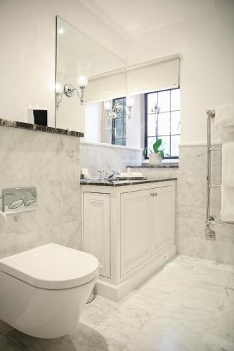 a white bathroom with a toilet and a sink at Lucknam Park Hotel in Chippenham