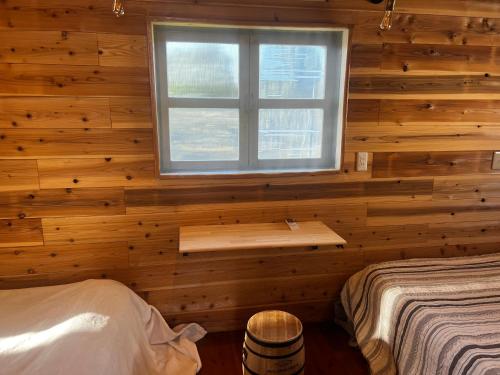 1 dormitorio con ventana en una pared de madera en Glamping Village LEAF en Mashiki