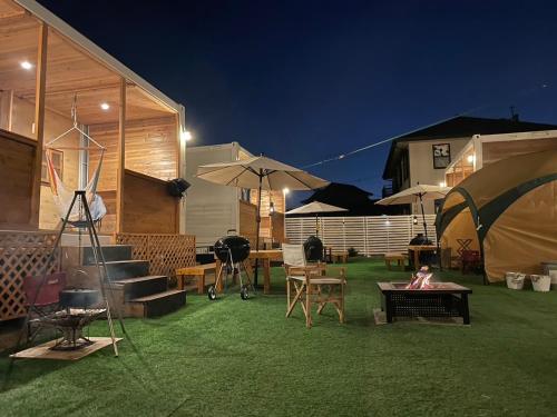 a yard with grass and tables and umbrellas at night at Glamping Village LEAF in Mashiki