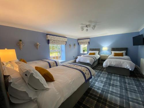 a bedroom with three beds in a room with blue walls at The Farmhouse in Pontefract