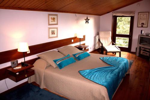 a bedroom with a large bed with blue pillows at Cork Tree Villa in Gondomar