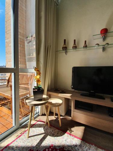 a living room with a flat screen tv and two stools at Apartamento na Berrini próximo ao WTC in São Paulo
