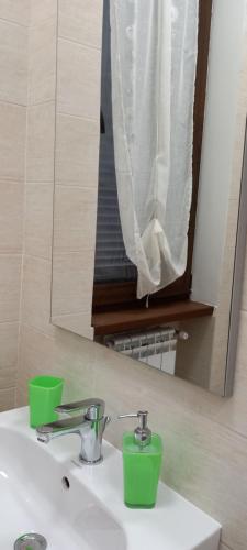 a bathroom sink with two green cups and a mirror at B&B LE BACETTE in Caprarola