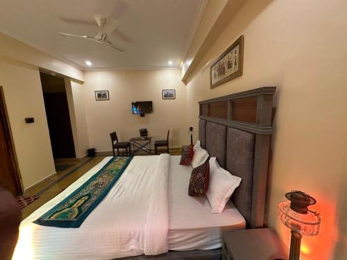 - une chambre dotée d'un grand lit avec des draps et des oreillers blancs dans l'établissement BALARWA HAVELI, à Jodhpur