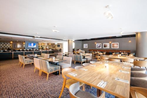 a restaurant with tables and chairs and a bar at Holiday Inn Coventry M6, J2 by IHG in Coventry