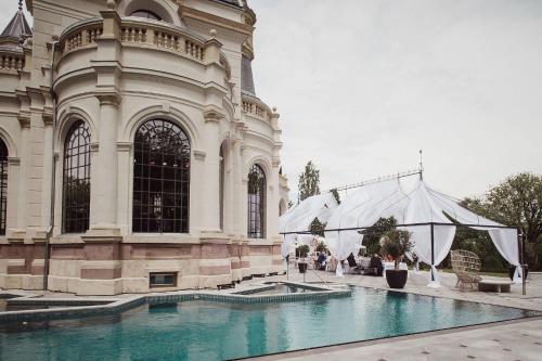un gran edificio con una piscina frente a él en BOTANIQ Castle of Tura - Small Luxury Hotels of the World, en Tura