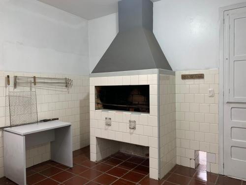 a kitchen with a fireplace in a white tiled room at Pousada Hostel Dodora in Bento Gonçalves