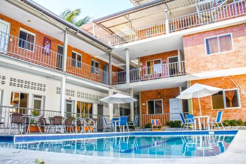 a swimming pool in front of a building with chairs and umbrellas at Victoria Imperial Hotel in Mariquita