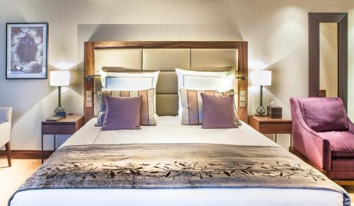 a bedroom with a large bed and a pink chair at AlpenGold Hotel Davos in Davos