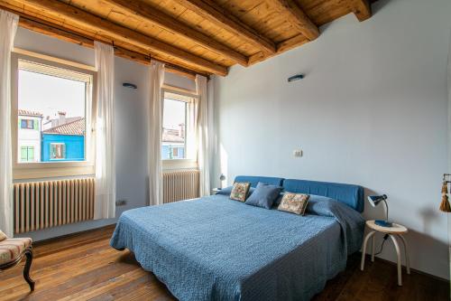 a bedroom with a blue bed and a window at Wondrous Palazzetto 1619 in Magical Burano Island in Burano