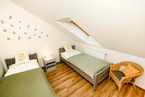 a attic room with two beds and a chair at Benešovka in Vacov