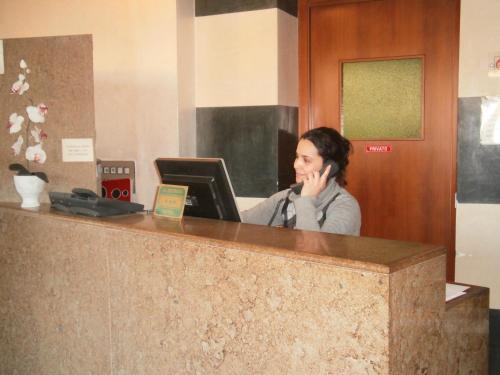 a woman talking on a phone at a reception desk at Albergo Villa & Roma in Palazzolo sullʼOglio