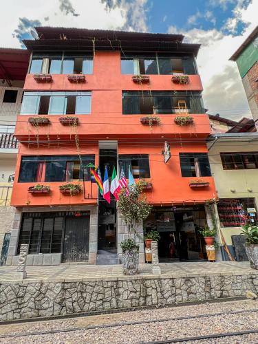 an orange building with flags in front of it at Nativus Hostel Machu Picchu in Machu Picchu