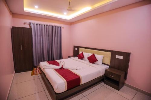 a bedroom with a large bed with red pillows at zanbaq residency in Vythiri