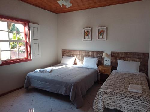 een slaapkamer met 2 bedden en een raam bij Casa do Aconchego in Tiradentes