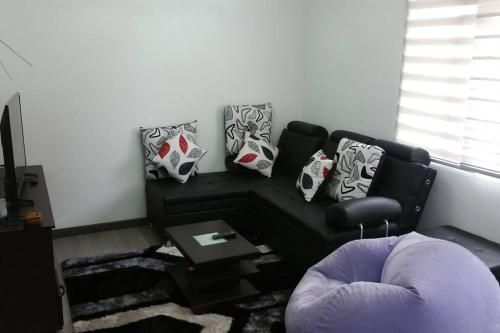 sala de estar con sofá negro y almohadas en Apartamento amoblado Central 148, en Bogotá