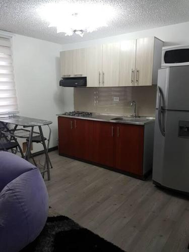 a kitchen with a table and a white refrigerator at Apartaestudio amoblado, Edificio el eden 148 in Bogotá