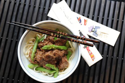 a bowl of noodles with meat and chopsticks on a table at The Retreat at Froog Moore Park in Tamworth