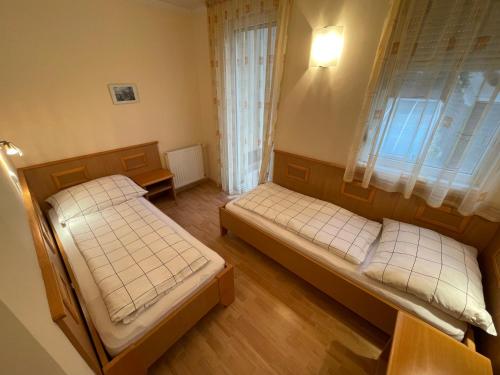 Duas camas num pequeno quarto com uma janela em Garda Apartman em Hévíz