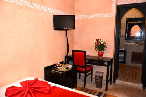 a bedroom with a bed and a desk with a tv on the wall at Riad Dar La Rose in Marrakech