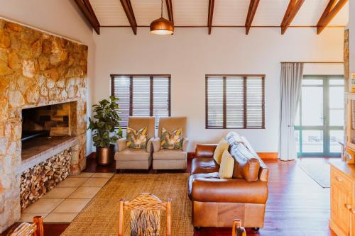a living room with couches and a stone fireplace at Blue Crane Farm Lodge in Botrivier