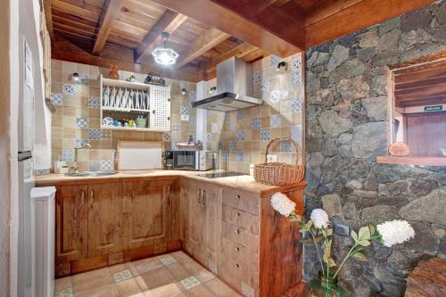 a kitchen with wooden cabinets and a stone wall at Casa Tía Eulalia in Frontera
