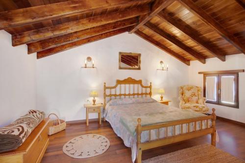 a bedroom with a bed and a chair and wooden ceilings at Casa Tía Eulalia in Frontera