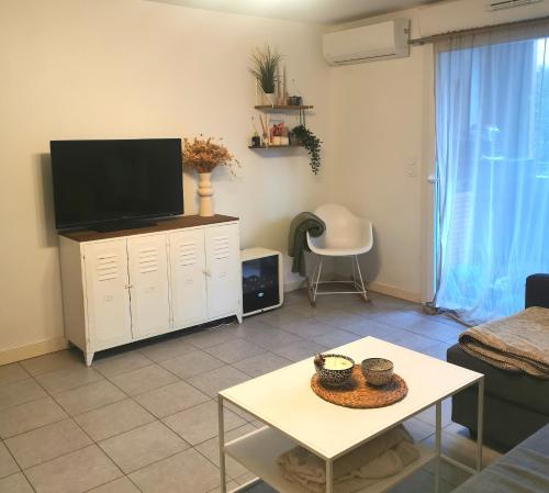 sala de estar con TV y mesa en Capbreton Superbe appartement avec parking en Capbreton