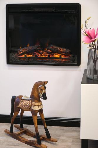a wooden rocking horse in front of a fireplace at Monos Apartman in Tatabánya