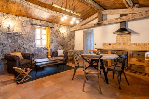 - un salon avec une table, des chaises et un mur en pierre dans l'établissement A VIGNA - CASEDDU PETRU GHJASEPPU vue mer et piscine, à Viggianello