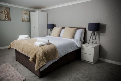 a bedroom with a large bed with white sheets and pillows at Abbeygreen House in Lanark