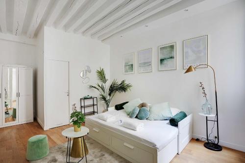 - une chambre blanche avec un lit et des oreillers bleus dans l'établissement Magnificent studio - 2P - Les Halles, à Paris