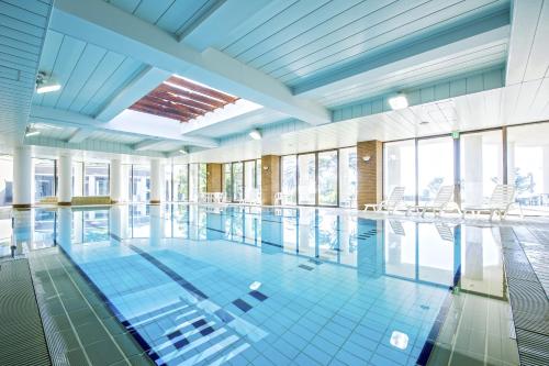 a swimming pool in a building with windows at Hotel Village Izukogen in Ito