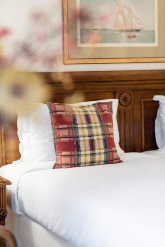a bed with a plaid pillow on top of it at Hotel Le Plaza Brussels in Brussels