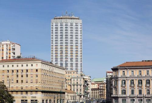 een hoog gebouw midden in een stad bij NH Napoli Panorama in Napels