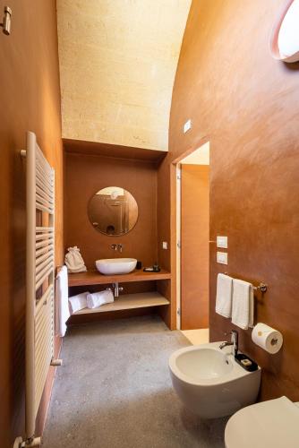 a bathroom with a sink and a toilet and a mirror at Il Giardino Grande - Dimora in Salento in Parabita